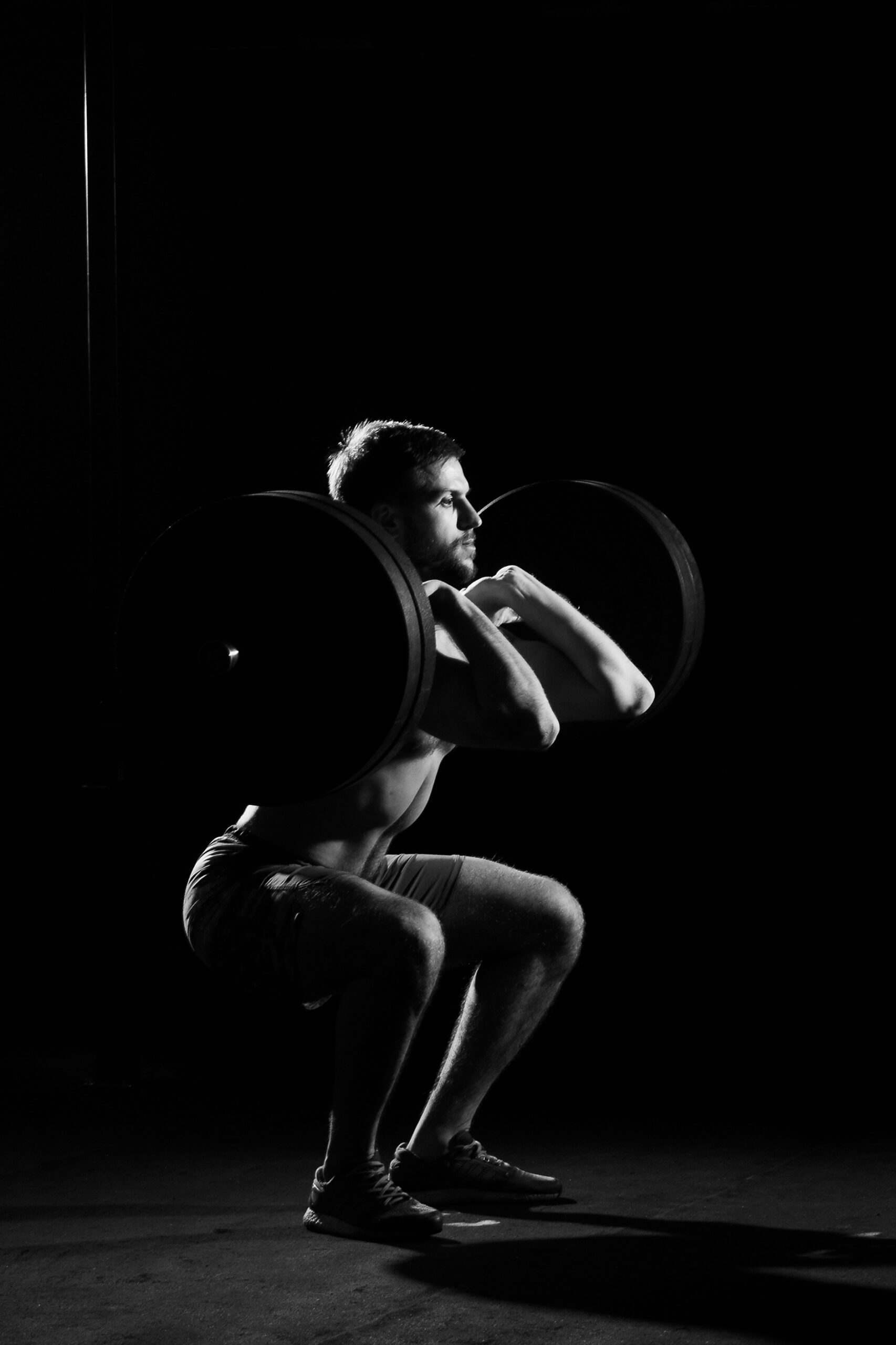 Fitness training. Man doing sit ups with weights in dark gym.